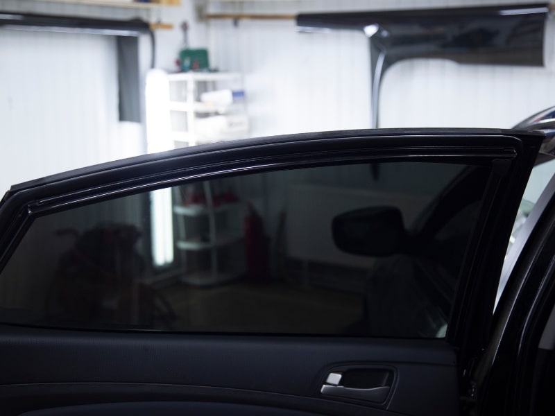 DIY side window repair risk shown: Bubbled, poorly applied window tint on a car door.