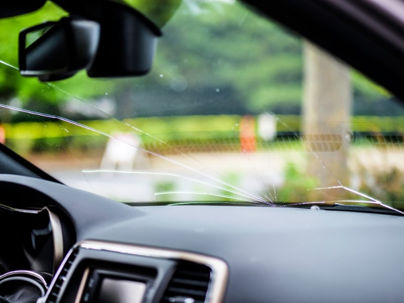 Close-up of windscreen cracks while driving, showing damage from the inside of a car.