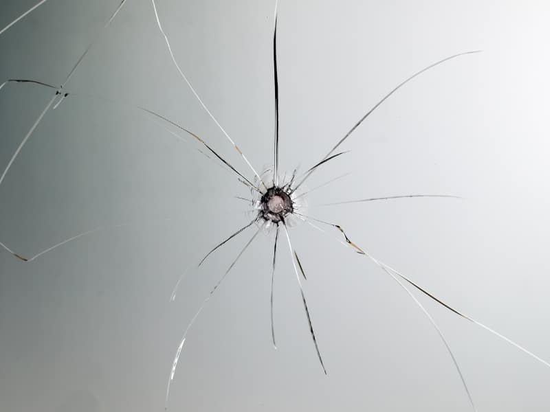 Close-up of a circular star crack showing early-stage car windscreen damage on clear safety glass.