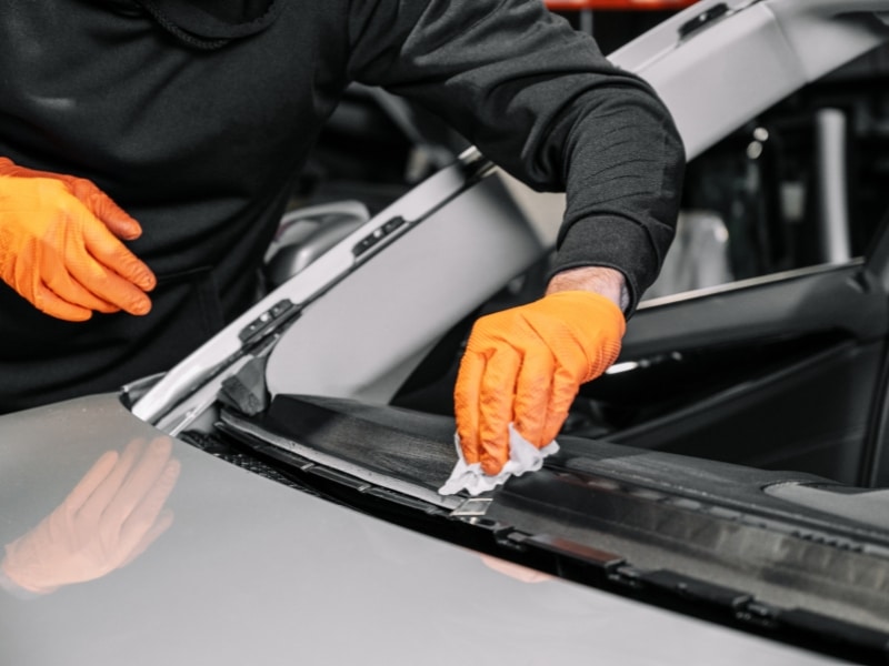 Mechanic cleaning glass frame showing how much does it cost to fix a car window