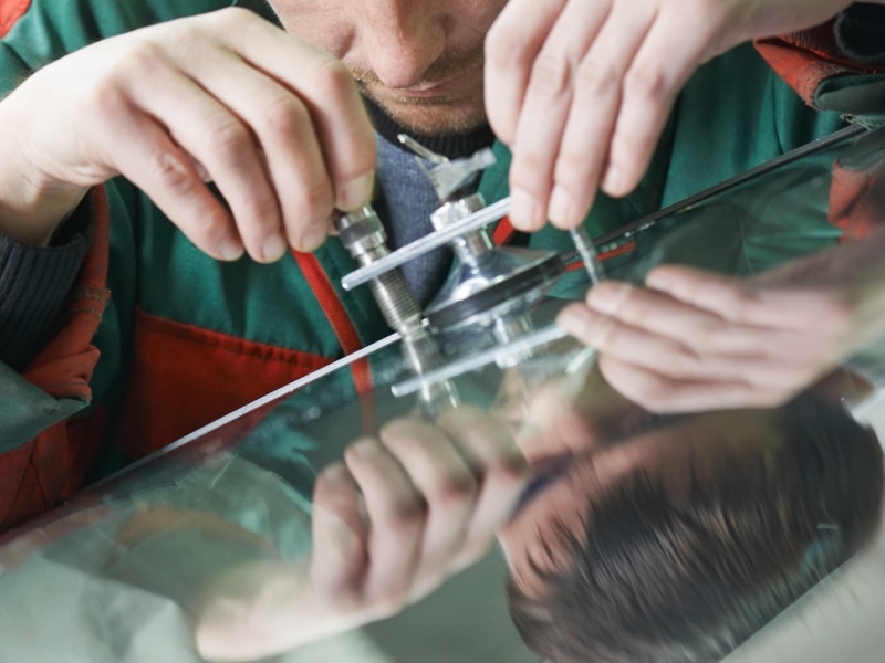 Technician repairing rear window of the car using specialised tool
